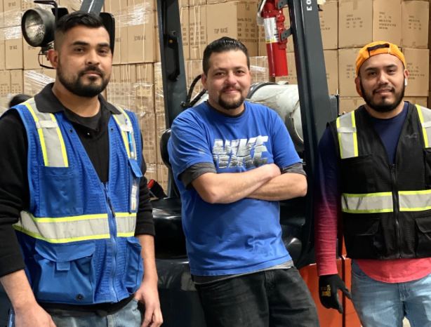 MPIO warehouse team standing in front of stacked inventory
